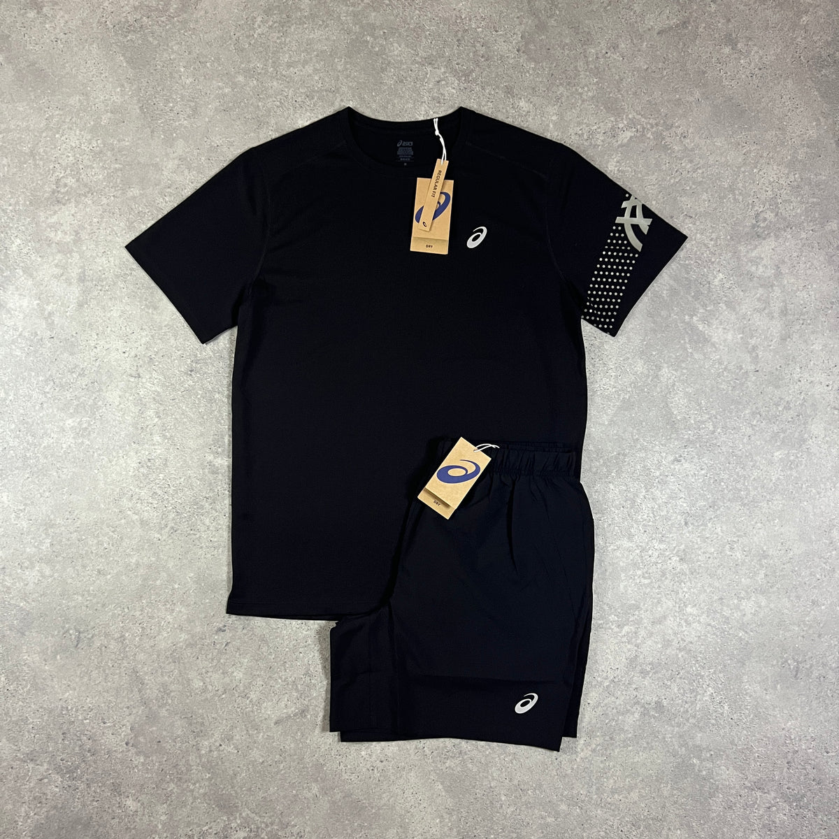 ASICS Icon T-Shirt & Core Shorts Set Black – black crew-neck t-shirt with white ASICS chest logo and  sleeve panel logo, paired with black core shorts with ASICS logo, flat lay on concrete surface with tags attached
